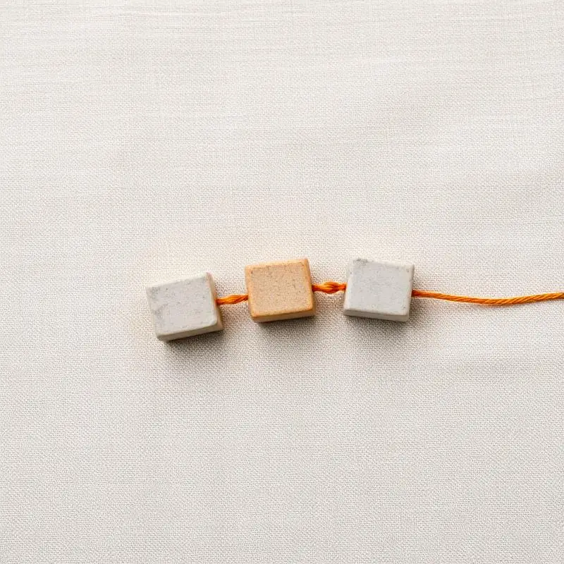 Three small stone blocks connected by an orange thread — value chain.